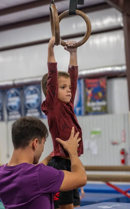 Young male gymnast demonstrating strength on gymnastics rings